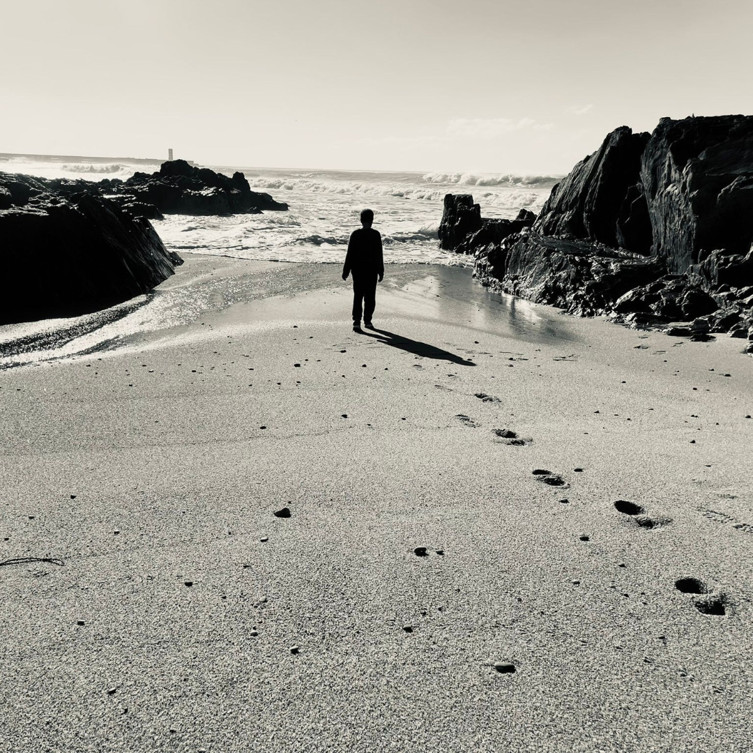 Black and white peaceful photo of child standing facing the sea.